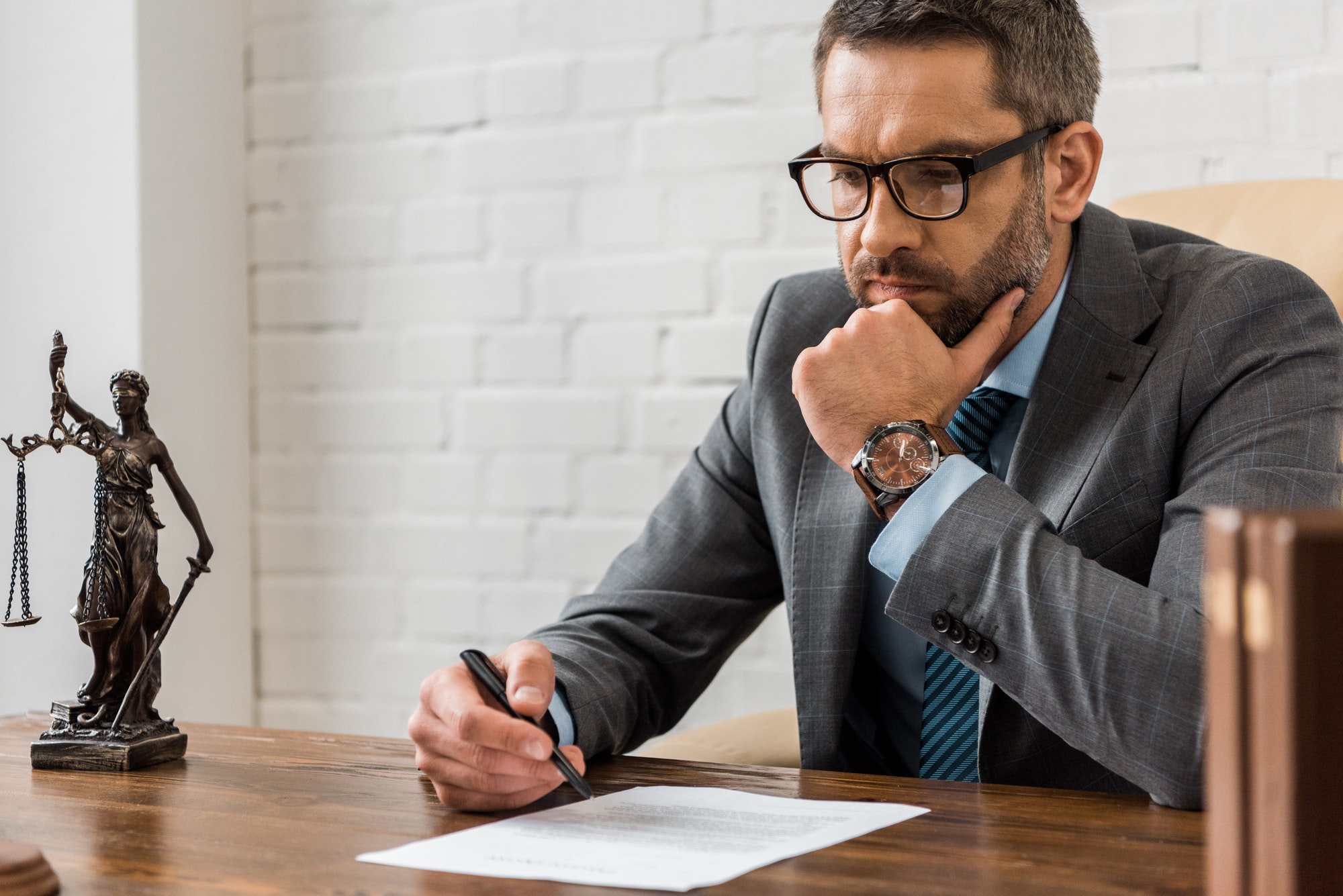 focused-male-lawyer-in-eyeglasses-working-with-contract-in-office.jpg